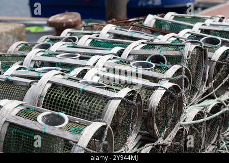 Pile di vasi da pesca verdi e bianchi attendono di essere dispiegati in un porto marittimo, segnalando una vivace industria della pesca. Foto Stock