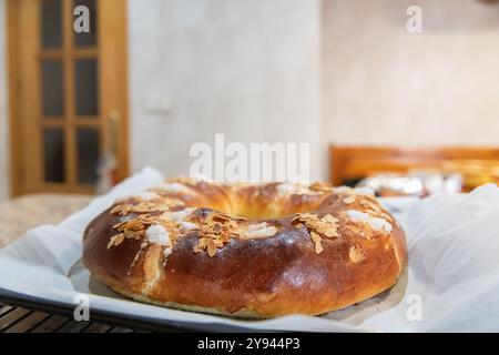 Una torta Three Kings appena sfornata, adornata con mandorle affettate e glassa di zucchero, si siede su un bancone della cucina e la calda atmosfera mette in risalto Foto Stock