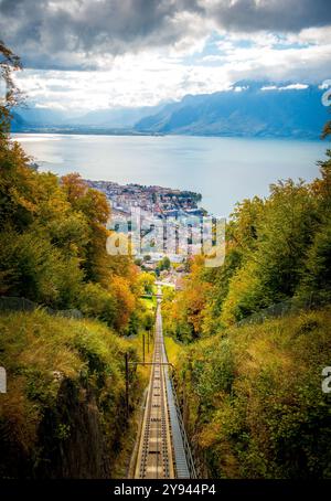 Una splendida scena autunnale con vista su Vevey, Svizzera, che mostra un fogliame vivace lungo un percorso della funicolare con il lago Leman e le Alpi nel dis Foto Stock