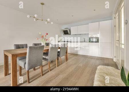 Una cucina moderna ed elegante e sala da pranzo con tavolo in legno, sedie grigie e design minimalista. Foto Stock