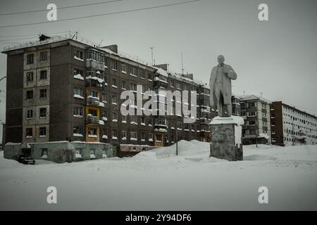 La città fantasma di Vorkuta, in Russia, con l'edificio dell'era del socialismo, le strade coperte di neve e il monumento di Vladimir Lenin. Foto Stock