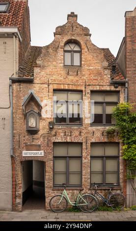 Belgio, Fiandre, Bruges, Oude Gentweg, biciclette fuori casa vecchia nella zona suburbana, all'ingresso delle almshouses religiose di Kattepoortje Foto Stock