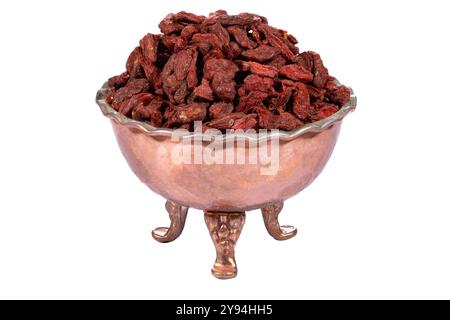 Bacche di goji essiccate in una ciotola decorativa in rame dallo stile rustico, isolata su sfondo bianco Foto Stock