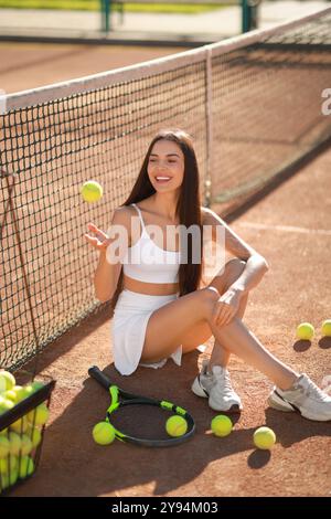 Bella donna che lancia palla da tennis sul campo Foto Stock