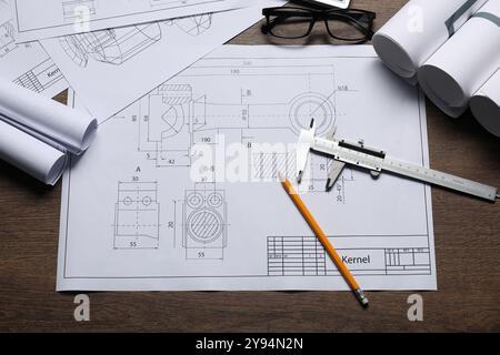 Diversi disegni tecnici, vetri, calibro a corsoio e matita su tavolo in legno, piano Foto Stock