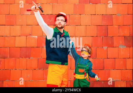 Fratelli che sognano di carriera futura in architettura o costruzione. Costruzione di utensili. Il ragazzino con un martello effettua le riparazioni. Foto Stock