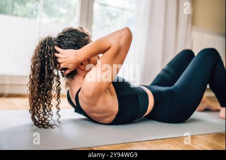 Primo piano di una donna caucasica bianca che esegue crunches (o sit-up) su un tappetino da yoga a casa (di Ivan Radic) Foto Stock