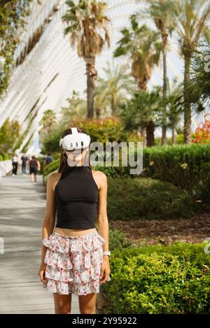 Una giovane donna in VR Gear esplora un bellissimo paesaggio tropicale, godendosi la sua avventura Foto Stock