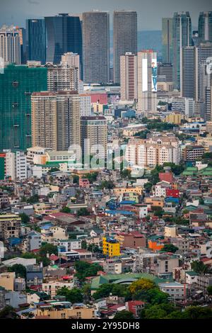 Manila, Luzon, Filippine - 19 maggio 2023: Il sole tramonta diffonde una luce calda attraverso la metropoli urbana, un mix ambientale intenso e popolato Foto Stock