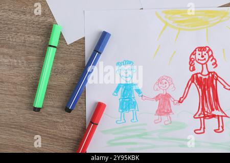 Disegno per bambini di una famiglia felice e penne in feltro su un tavolo in legno, vista dall'alto Foto Stock