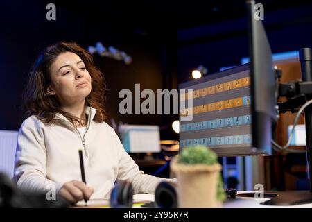 Un editor di foto sorridente che modifica le immagini, corregge il colore in un'azienda di post-produzione utilizzando una tavoletta grafica. Fotografo felice che corregge le foto sovraesposte con lo stilo sul dispositivo touchscreen Foto Stock