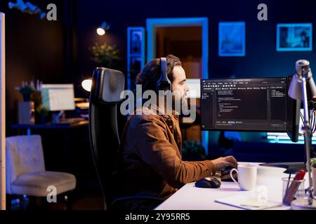 Programmatore freelancing che ascolta musica durante la progettazione e lo sviluppo di applicazioni software. Specialista IT che indossa le cuffie, implementando e gestendo i sistemi aziendali Foto Stock