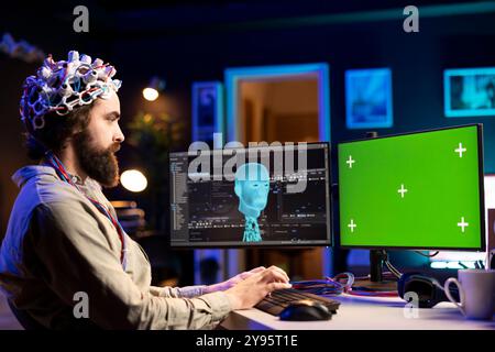 Software ENGINEEG con auricolare EEG che inizia a caricare la mente su un PC con schermo verde, cercando di ottenere poteri bionici. Amministratore IT che usa attrezzature neuroscientifiche ad alta tecnologia e computer di mockup Foto Stock