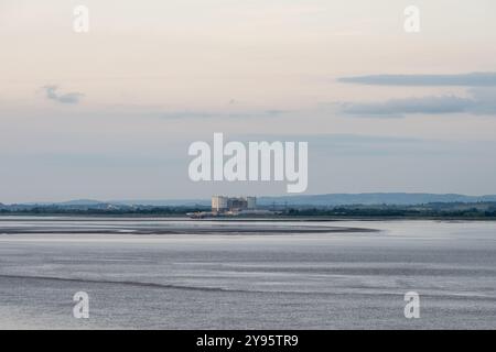 Il crepuscolo cade sopra la centrale nucleare di Oldbury e la scarpata Cotswolds Edge nel Gloucestershire, come si vede dall'estuario del Severn. Foto Stock