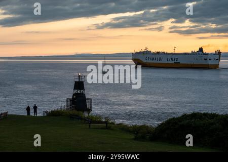 Una grande nave da carico e un piccolo yacht a vela passano nel Canale di Bristol al largo della costa di Portishead nel Somerset. Foto Stock