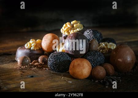 Vari dolci al cioccolato, come praline, biscotti e dolciumi alle noci su tavole di legno marrone scuro, spuntini festivi, spazio per copie, selezione di Foto Stock