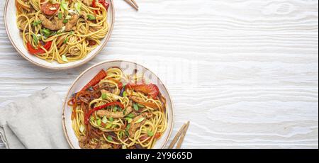 Due ciotole con Chow Mein o lo Mein, tradizionali spaghetti cinesi con carne e verdure, serviti con bacchette e vista dall'alto su bianco rustico Foto Stock