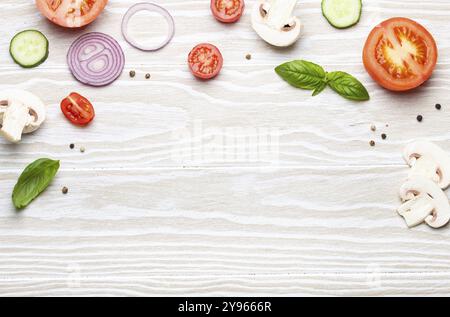 Cucina di base: Preparati ingredienti freschi, basilico, pomodori ciliegia, funghi, cetriolo tagliato, cipolla, peperoncino, spezie su legno bianco bac Foto Stock