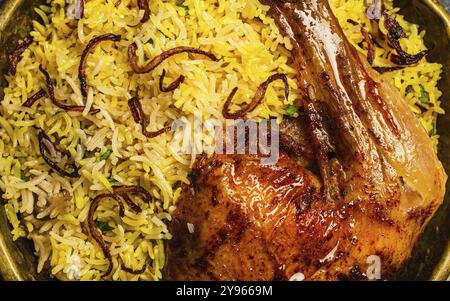 Primo piano macro di delizioso piatto indiano Biryani coscia di pollo con riso basmati in metallo ottone vecchio recipiente. Cibo tradizionale non vegetariano dell'India, top v Foto Stock