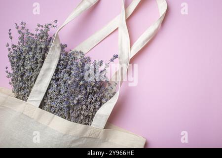 Bouquet di fiori di lavanda in borsa per shopper in lino eco beige con vista dall'alto su sfondo viola. Romantico sfondo femminile primaverile o estivo, ideale per Foto Stock