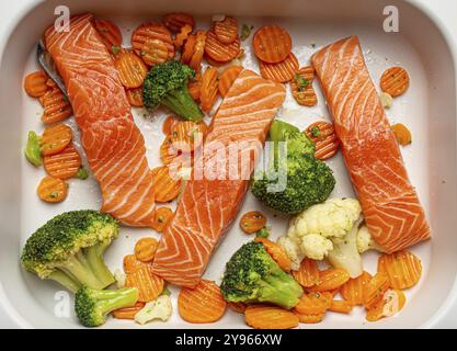 Vista dall'alto della casseruola con pesce crudo crudo, bistecche di salmone, broccoli, cavolfiore e carote. Preparazione di una sana cena a basso contenuto di carboidrati, per Foto Stock