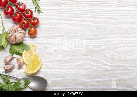 Composizione sana degli ingredienti alimentari con pomodori ciliegini freschi, erbe, spicchi d'aglio, spicchi di limone e cucchiaio su fondo rustico in legno bianco, overh Foto Stock