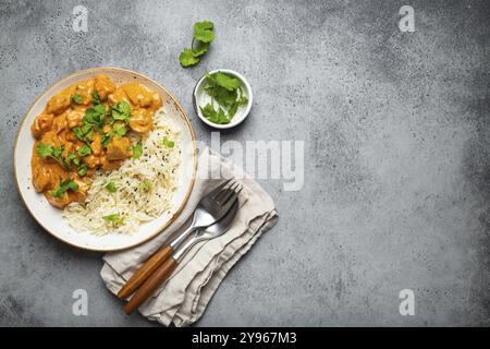 Piatto tradizionale indiano curry di pollo con riso basmati e coriandolo fresco su piatto bianco rustico su fondo grigio tavolo in cemento dall'alto. Indiano Foto Stock