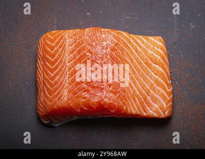 Filetto di salmone fresco norvegese crudo su sfondo rustico marrone scuro, nutrizione e dieta salutari, fotografia gastronomica Foto Stock