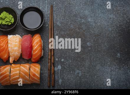 Set di sushi e panini giapponesi tradizionali con vista dall'alto con salsa di soia e bacchette su sfondo rustico in pietra. Sushi con salmone, tonno e gamberi, spa Foto Stock