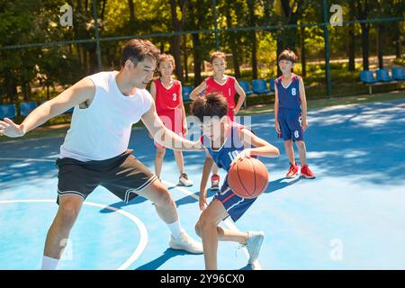 Coach che insegna ai bambini come giocare a basket Foto Stock