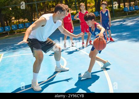 Coach che insegna ai bambini come giocare a basket Foto Stock