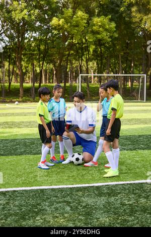 Allenatori e bambini in classe di allenamento calcio Foto Stock