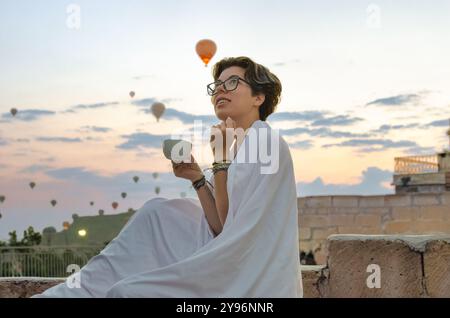 Giovane donna che guarda le mongolfiere e il bellissimo paesaggio mattutino di Goreme, viaggia in vacanza in Cappadocia, Turchia Foto Stock