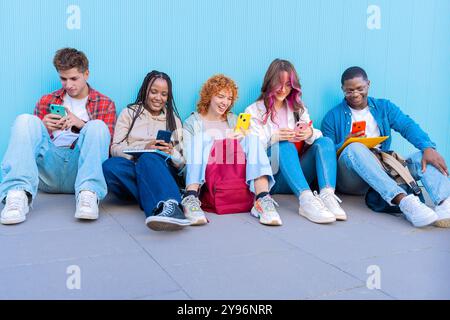 Diversi giovani seduti all'aperto con smartphone Foto Stock