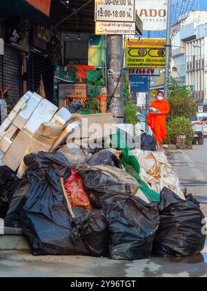 Un monaco visto camminare tra pile di rifiuti lungo la strada, gettato dai residenti dopo che le acque si sono ritirate. Dopo che la situazione delle inondazioni a Chiang mai si placò, i monaci di vari templi locali ripresero la loro elemosina, come al solito, in una città piena di rifiuti di oggetti danneggiati dalle inondazioni, fango e polvere dai sedimenti lasciati dietro dalle acque in ritirata. Sebbene le autorità governative e i residenti abbiano iniziato a pulire l'area e a rimuovere i detriti, molti punti sono ancora coperti di fango e polvere accumulati. Ci vorranno diverse settimane prima che la situazione torni alla normalità. (PH Foto Stock