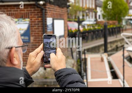Uomo dai capelli bianchi che fotografa Henley Boats e l'Angel Pub con smartphone Foto Stock