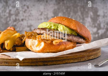 Hamburger con cipolla caramellata e avocado su un tagliere di legno Foto Stock