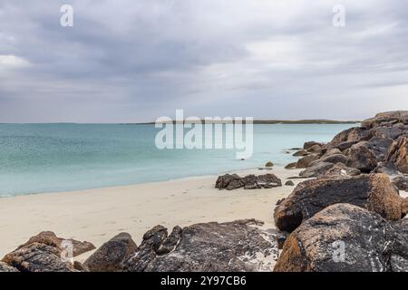 La spiaggia di Gurteen al tramonto offre acque turchesi cristalline e una costa rocciosa in Irlanda. La soffice sabbia bianca contrasta con rocce scure e intemperie Foto Stock