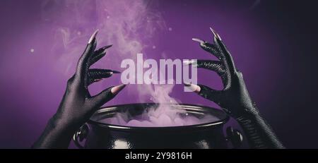 Le mani della strega con artigli affilati in guanti neri che si librano su un calderone fumante pieno di pozione viola, atmosfera mistica e inquietante, Halloween Foto Stock