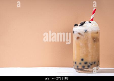 Classico boba bobble tea con perle di tapioca e crema non casearia montata sopra il bicchiere, dolce dolce dolce estivo su sfondo bianco della tavola c Foto Stock