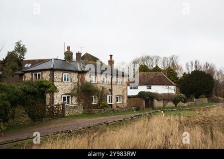 Un affascinante cottage in pietra focaia e mattoni annidato nella tranquilla campagna di Alfriston, che mostra la serena bellezza della vita rurale inglese. Foto Stock