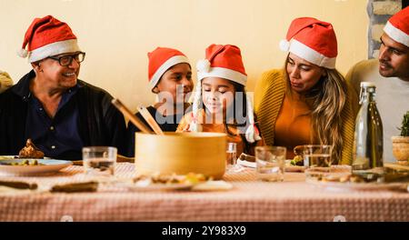 Famiglia latina felice divertirsi a mangiare insieme durante il periodo natalizio - concetto di vacanza - attenzione principale sul volto dei bambini Foto Stock