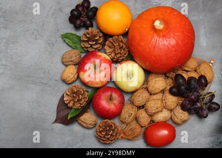 Composizione autunnale con mele, noci e foglie su sfondo grigio Foto Stock