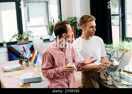 Due uomini eleganti si impegnano in una discussione vivace mentre lavorano in un ambiente luminoso. Foto Stock