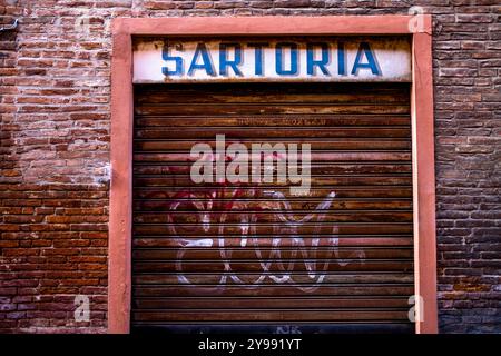 facciata di un negozio sartoriale chiuso a lungo con un cartello vintage e un cancello arrugginito dal tempo Foto Stock