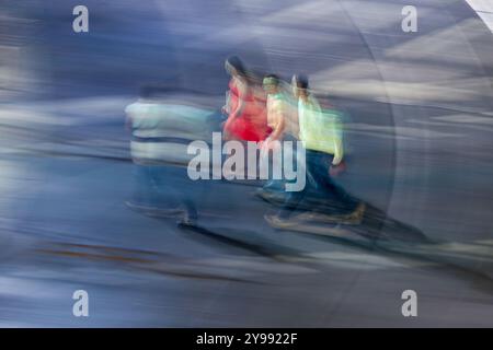 Panning shot per catturare la sfocatura dinamica del movimento delle persone che camminano in un paesaggio urbano di notte, illustrando movimento ed energia. Foto Stock