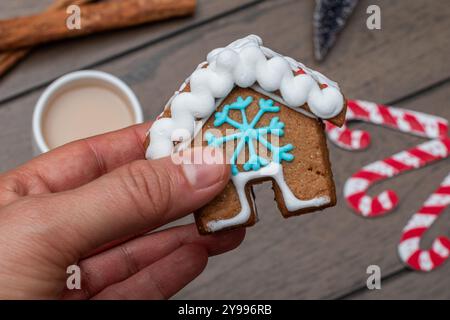 Donna che tiene in mano una casa di pan di zenzero. Sfondo in legno. Natale Foto Stock