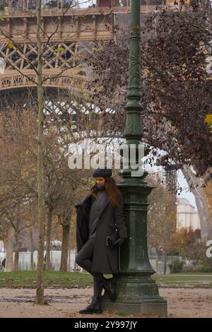 Elegante giovane donna che passeggiava per il parco autunnale con la Torre Eiffel sullo sfondo Foto Stock