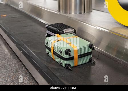 Trasporto bagagli presso l'aeroporto Gatwick di Londra, Regno Unito, nell'area di ritiro bagagli dell'aeroporto. Valigie sulla cintura Foto Stock