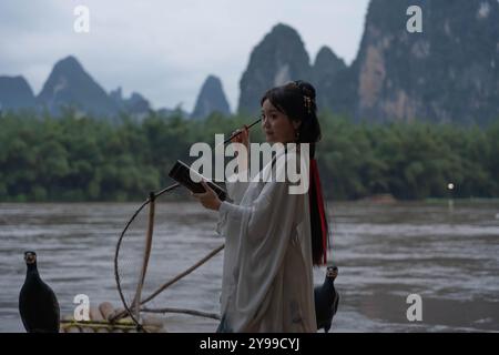 Foto media della bella signora di Hanfu con la quill di fronte al paesaggio panoramico di Xingping, Cina Foto Stock